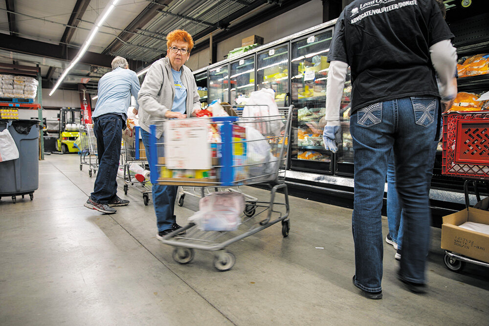 COMMUNITY AID: Least of These volunteers prepare shopping carts filled with products for clients on a recent distribution day.